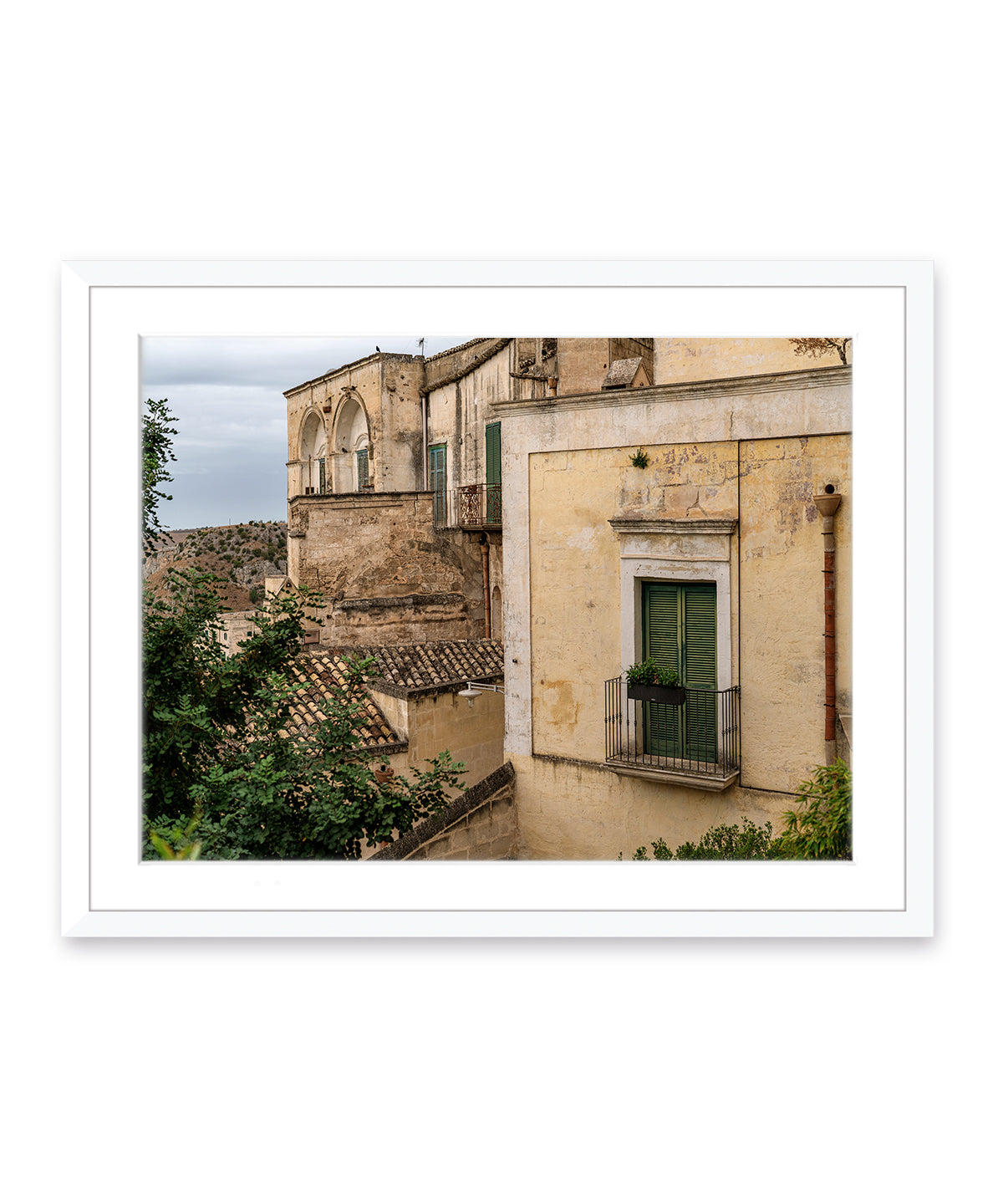 Italy wall art featuring historic buildings in Matera, Italy with muted green and yellow hues in white frame