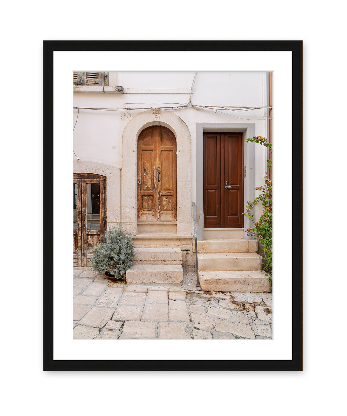 italy photograph in black frame featuring weathered doors and cobblestone street in Conversano, Puglia.