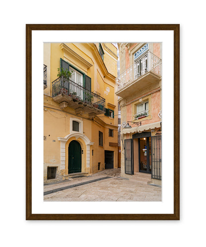 Framed italy photograph featuring yellow and pink facades with textured plaster walls in a dark wood frame.