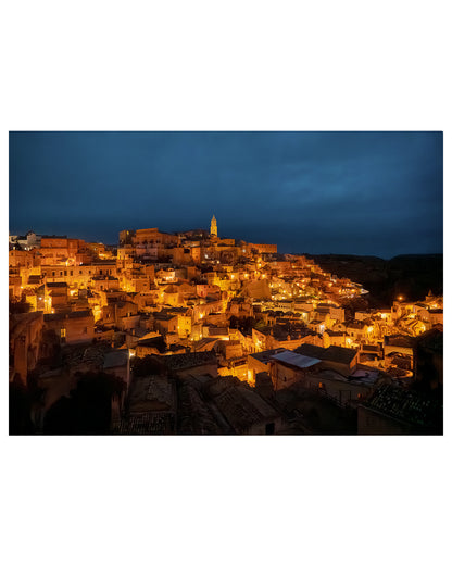  Matera, Italy night photograph with glowing amber city lights against a dark sky.