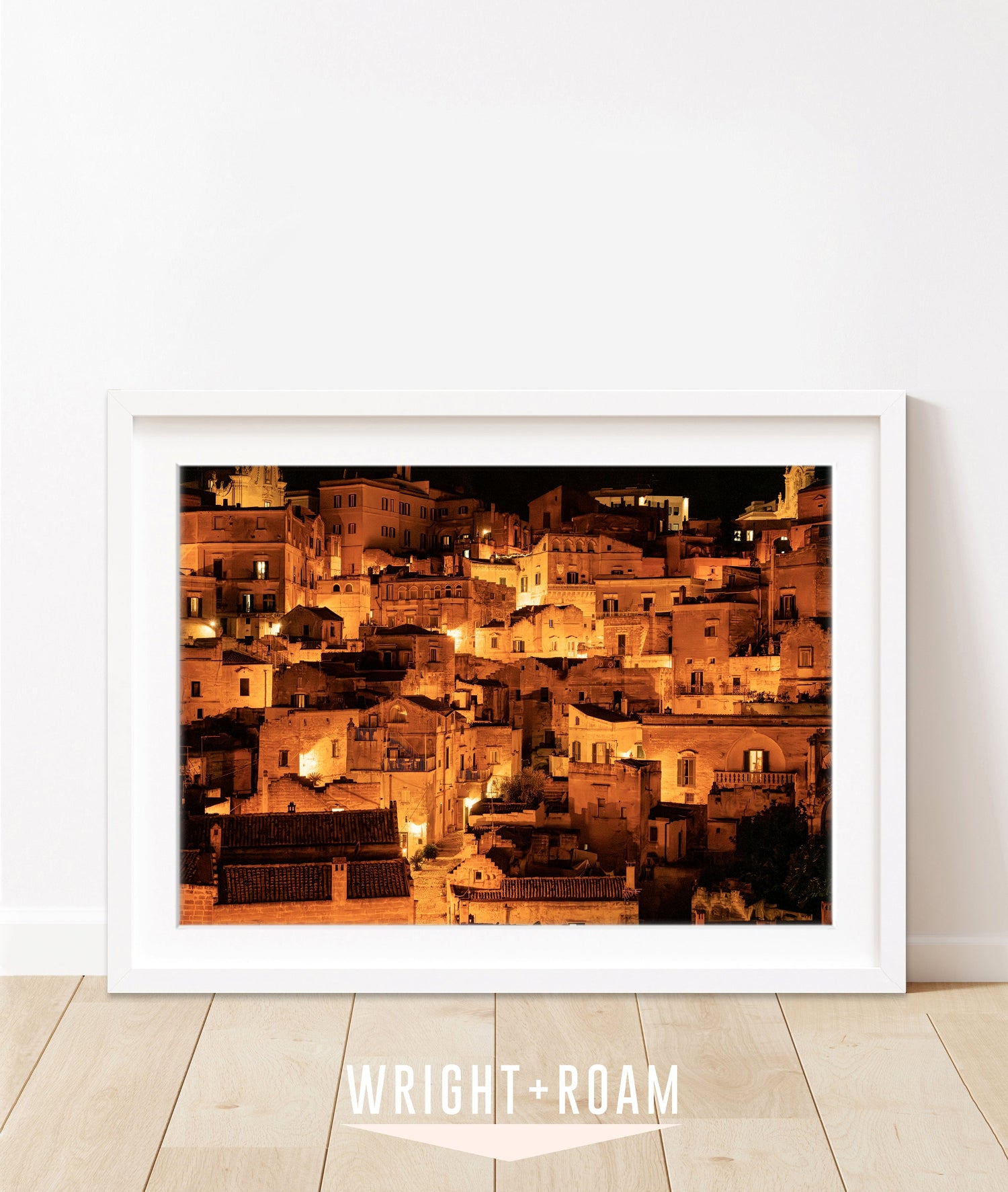 Framed photograph of Matera, Italy at night with glowing amber streetlights and historic stone buildings.