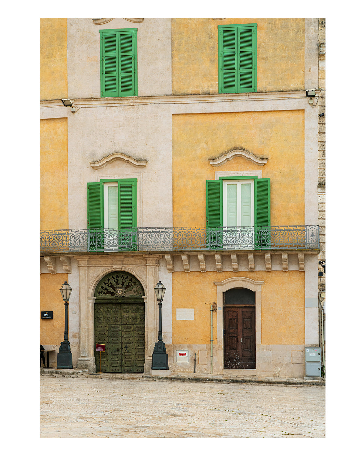 Fine art photograph of a historic building facade in Matera, Italy, featuring soft yellow and green tones and architectural symmetry.