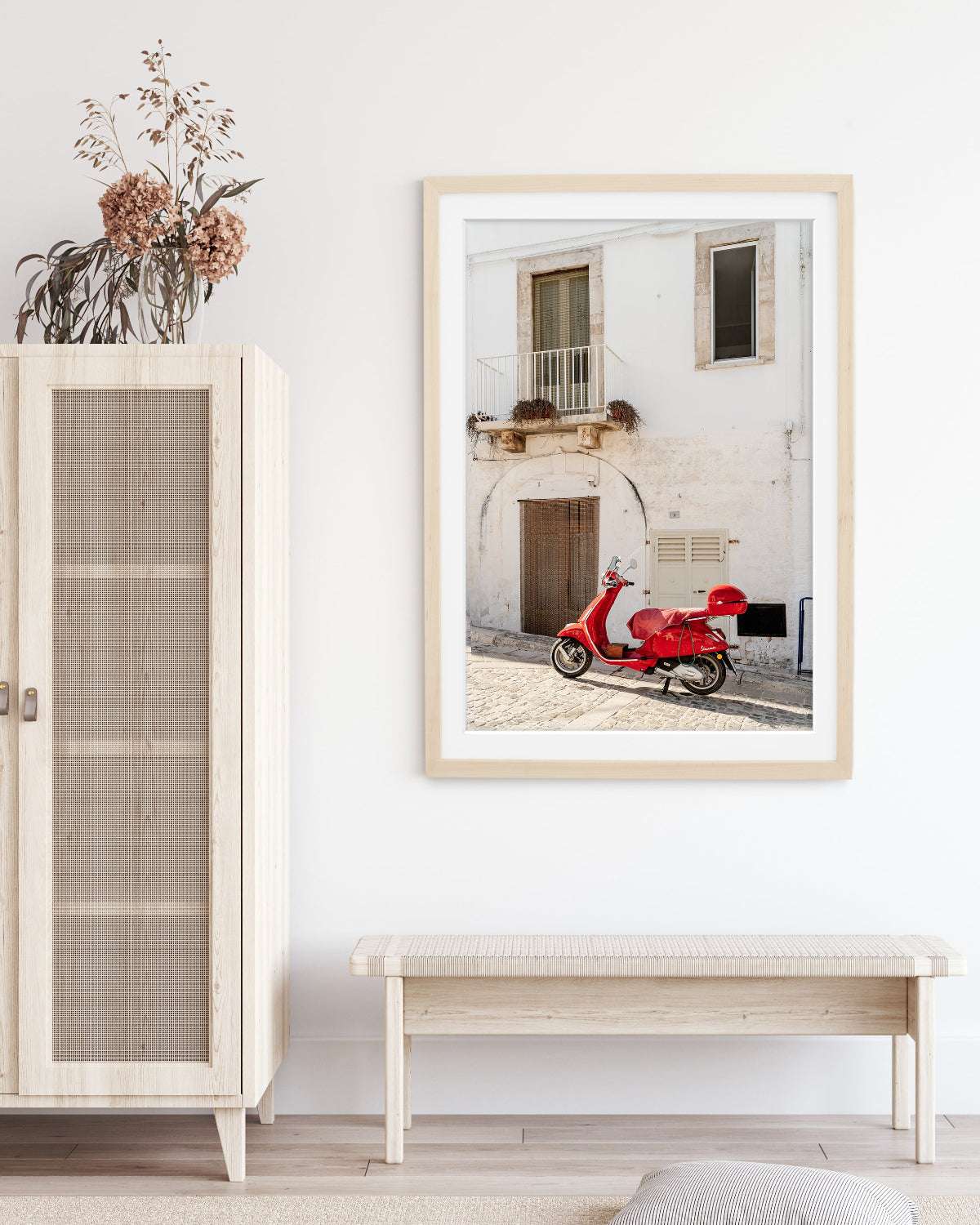 neutral decor featuring framed weathered building in italy accented by red moped.