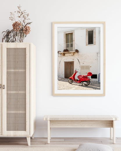 neutral decor featuring framed weathered building in italy accented by red moped.