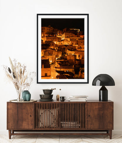 European inspired entrway featuring dark wood table and  framed fine art photograph of Historic city of Matera, Italy at night with glowing amber lights.