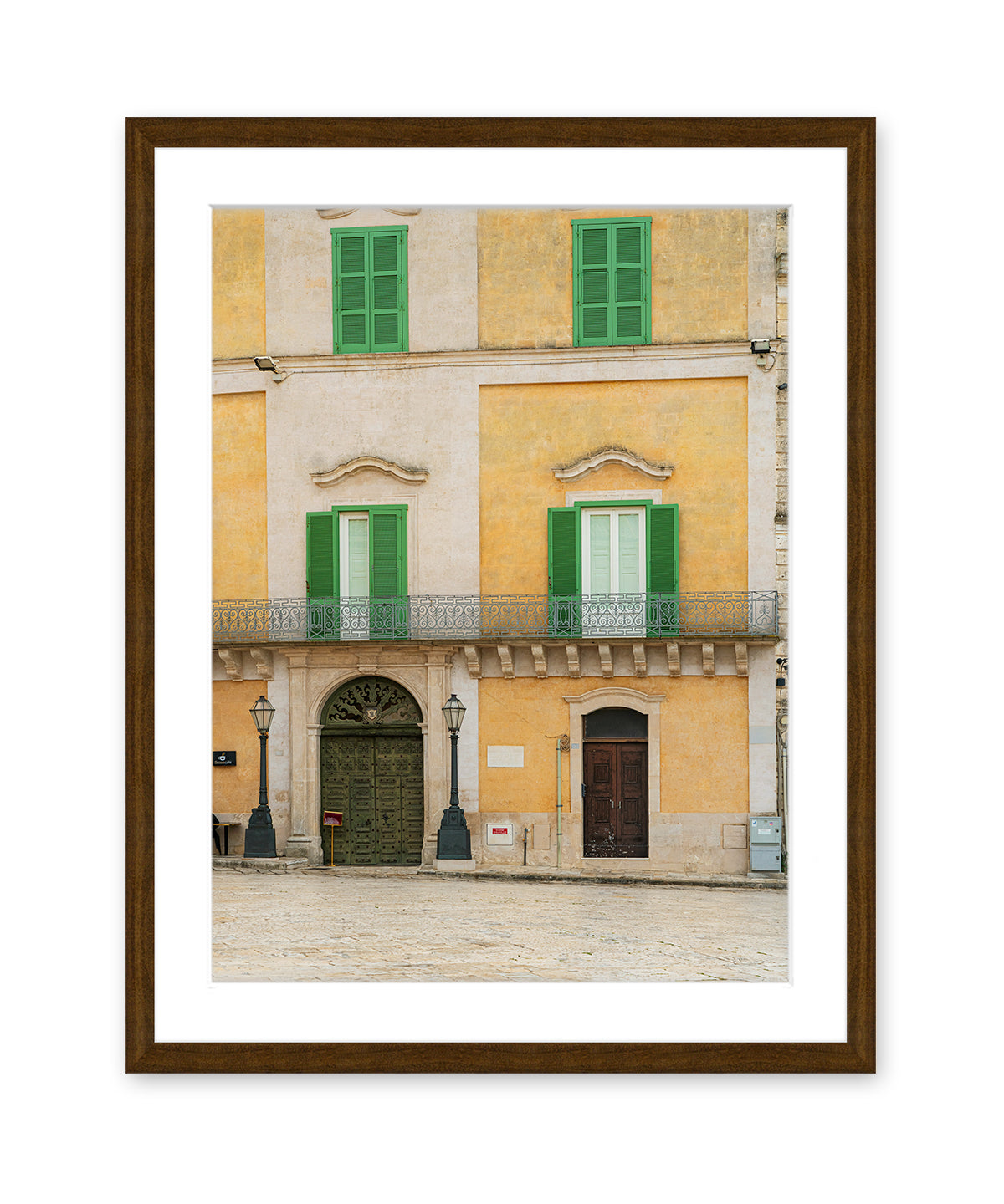 Fine art photograph in dark wood frame featuring a historic building facade in Matera, Italy filled with soft beige, yellow, and green tones and architectural symmetry