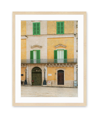 Fine art photograph in wood frame featuring a historic building facade in Matera, Italy filled with soft beige, yellow, and green tones and architectural symmetry